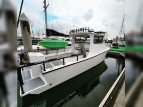 A sleek white boat docked at the marina, showcasing its clean lines and spacious deck, perfect for fishing or leisure outings.
