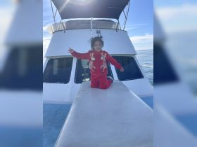 A joyful child poses on the deck of a boat, capturing the fun and excitement of a day on the water — perfect for family adventures.