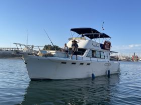 A group of individuals aboard a fishing boat at the marina, showcasing a perfect day for fishing and relaxation on the water.