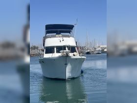 A front view of a yacht docked in the marina, showcasing its structure and design against a clear blue sky.
