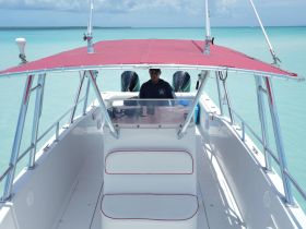 A view of the helm inside a boat, showcasing the captain at the console with a stunning turquoise backdrop — perfect for navigating the beautiful waters.