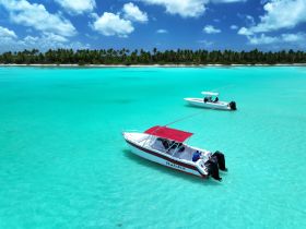 A stunning aerial view of two boats anchored in crystal-clear turquoise waters, surrounded by a lush tropical landscape — perfect for exploring the beauty of the Caribbean.
