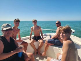 A cheerful family enjoys a sunny day on the boat, capturing moments of togetherness against the beautiful ocean backdrop.
