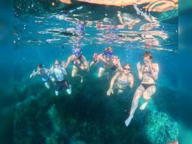 A lively group enjoys snorkeling underwater, showcasing their excitement with thumbs up in a vibrant marine environment — perfect for family adventures and aquatic exploration.