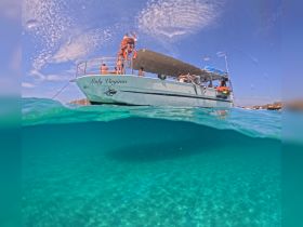 A vibrant underwater view of the 'Lady Virginia' boat with guests enjoying the clear waters — perfect for snorkeling adventures and exploring marine life.