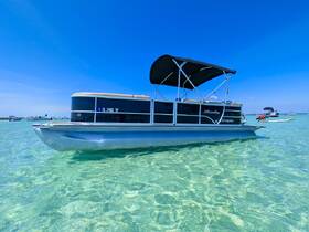A sleek Bentley pontoon boat anchored in crystal-clear waters, perfect for leisurely days on the water.