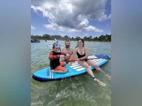A joyful family enjoys paddleboarding and snorkeling in shallow waters, creating unforgettable memories during their aquatic adventure.