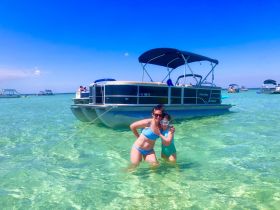 A mother and child enjoy a fun day swimming in clear waters next to their pontoon boat, creating lasting family memories during a sandbar stop.