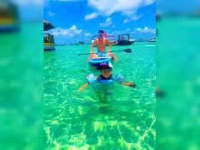 A fun-filled day on the water with a child swimming and an adult paddleboarding in crystal-clear waters, perfect for family adventures and water sports.