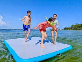 Three children enjoy a fun day on an inflatable mat in the water, showcasing the joy of summer activities and snorkeling adventures.