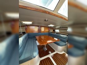Interior view of a cozy boat cabin featuring comfortable seating and a polished dining table, perfect for relaxing meals on the water.
