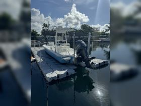 A pristine center console boat docked at a marina, showcasing its sleek design against a backdrop of clear skies and calm waters.