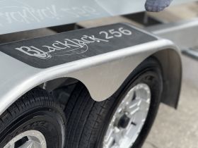 Close-up view of a boat trailer with the name 'Blackjack 256' visible, showcasing the design and wheel details.