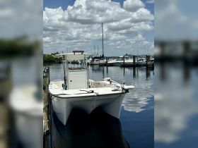 A sleek speedboat docked at the marina, reflecting the beautiful clouds above — perfect for a day out on the water.