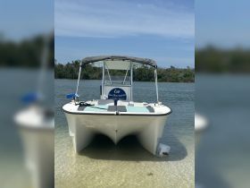 A clear view of a catamaran docked in shallow waters, showcasing its sleek design and inviting seating area, perfect for a day on the water.