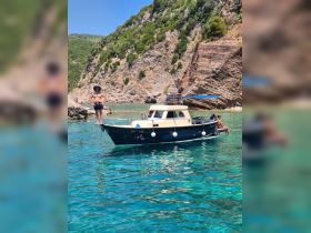 A sunny day on the water with guests enjoying a boat trip, showcasing the stunning turquoise waters and rocky coastline — perfect for summer adventures.
