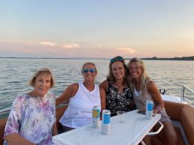 A group of friends enjoys a relaxing evening on the water, sharing drinks and laughter as they take in the beautiful sunset views from their boat.
