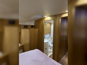 A cozy interior view of a boat cabin featuring wooden finishes and a bathroom area, ideal for comfortable cruising and overnight stays.