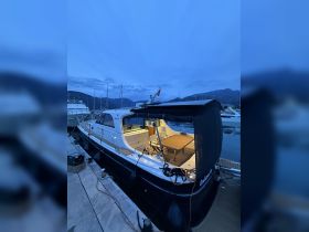 A beautifully lit yacht docked in the marina at twilight, showcasing its elegant design and inviting outdoor seating area.