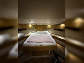 Cozy interior cabin of a boat featuring a comfortable bed and warm lighting, perfect for relaxing during a sailing trip.