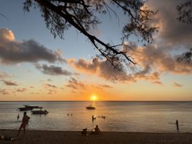 A picturesque sunset view at the beach with boats anchored nearby, capturing a serene moment of relaxation and enjoyment in the water.