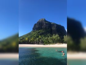 A stunning view of a tropical island with lush greenery and a beach, featuring a person snorkeling in the clear waters — an ideal destination for adventure and relaxation.