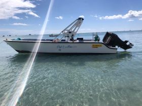 A clear view of the boat 'Pat & la Francilienne' docked in shallow waters, showcasing its sleek design against a beautiful sky.