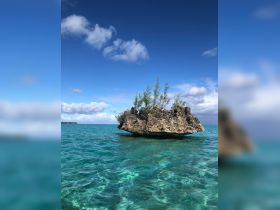 A stunning view of a rocky island surrounded by crystal-clear turquoise waters, showcasing the natural beauty of the coastline.