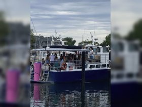 A lively group gathers on a party boat at the dock, perfect for celebrations and group outings on the water.
