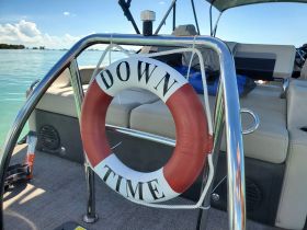 A close-up view of the interior of a boat featuring a lifebuoy labeled 'DOWN TIME' and comfortable seating, perfect for relaxing on the water.