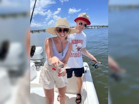 A couple proudly displays their catch while fishing on a sunny day, showcasing the excitement of a successful outing on the water.
