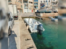 A pristine center console boat docked in a marina, showcasing its sleek design against a backdrop of waterfront buildings.