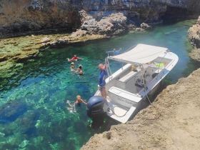 A lively group enjoys swimming in crystal-clear waters near a boat, creating unforgettable family memories in a stunning natural setting.