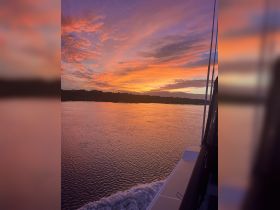A stunning sunset view from the deck of a boat, showcasing vibrant colors reflecting on the water — perfect for serene evening cruises.