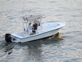 A fisherman navigates a speedboat through calm waters, showcasing the thrill of boating and fishing adventures.