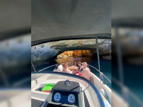 A group of friends enjoys a scenic boat ride exploring a stunning cave, capturing the moment with their cameras — perfect for adventure seekers and nature lovers.