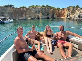A group of friends relaxes on a boat, enjoying drinks and the sun in a picturesque cove — the perfect summer getaway on the water.