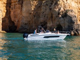 A group enjoys a scenic boat ride along the stunning coastline, showcasing the beauty of the cliffs and clear waters.