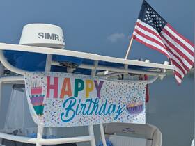A festive 'Happy Birthday' banner adorns the boat, setting the scene for a joyful celebration on the water.