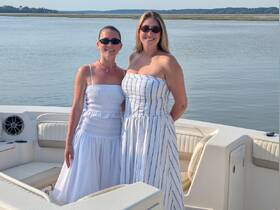 Two friends pose together on a boat, enjoying a sunny day on the water — perfect for memorable outings and celebrations.