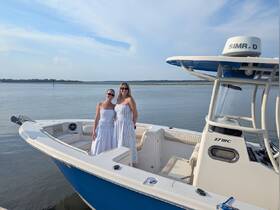 Two friends pose on the deck of a boat, enjoying a beautiful day on the water — perfect for memorable outings and celebrations.