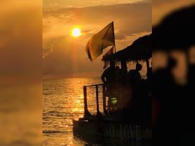 A stunning sunset view with silhouettes of guests enjoying their time on a boat, creating a perfect backdrop for memorable celebrations on the water.
