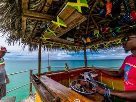 Inside view of a colorful boat helm with two individuals present, showcasing the vibrant atmosphere of a Jamaican tour experience.
