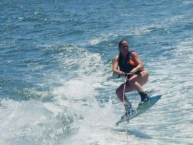 A thrilling moment captured as a woman enjoys wakeboarding on the water, showcasing the excitement of water sports and summer fun.