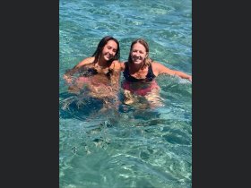 Two friends enjoy a refreshing swim in crystal-clear waters, capturing the essence of fun and relaxation during their boating adventure.