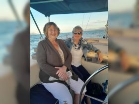 Two friends enjoy a sailing trip together, capturing the joy of companionship on the water.