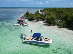 A vibrant scene at a sandbar with guests enjoying paddleboarding and swimming around two boats, perfect for a fun day on the water.