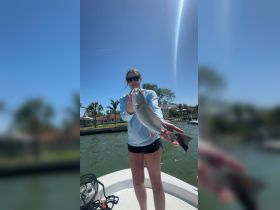 A proud angler holds up a freshly caught fish while enjoying a sunny day on the water — a perfect moment for fishing enthusiasts.