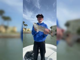 A young boy proudly holds up his catch while fishing, showcasing a successful day on the water. This moment captures the joy of fishing and the excitement of youth.
