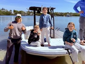 A joyful family enjoys their time on a boat, showcasing their finds like shells and rocks — a perfect day of adventure on the water.